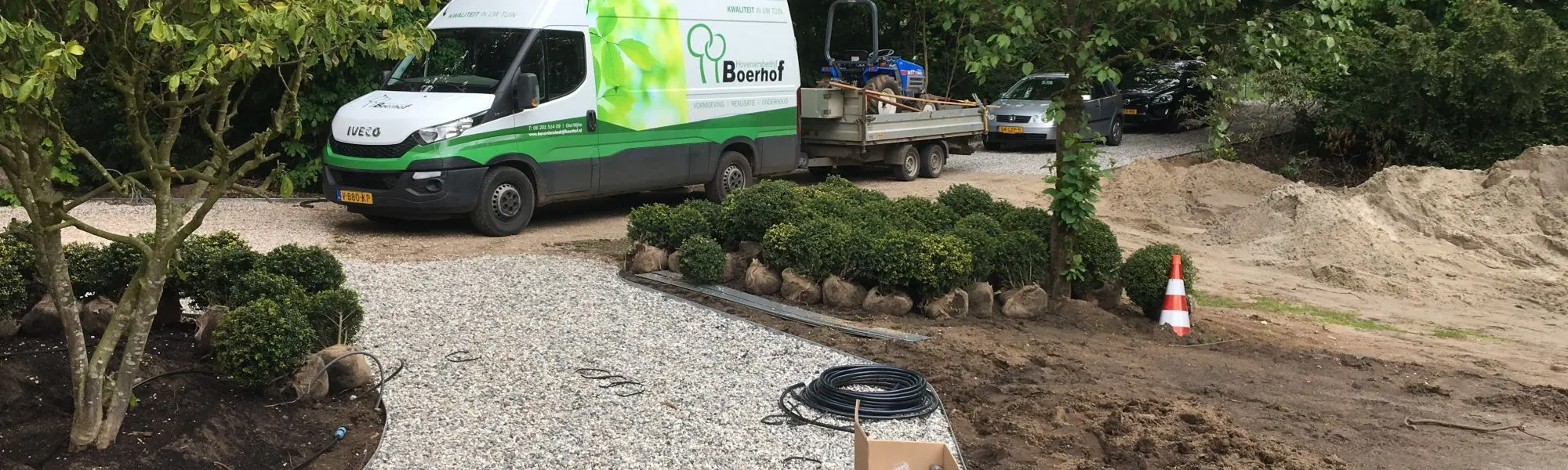 Hoveniersbedrijf Boerhof bezig met tuinaanleg: grindpad, buxusbollen en bomen worden geplaatst